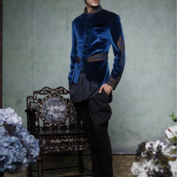 A royal blue, velvet bandhgala with intricate trellis work and gota embroidery on the sleeves, waist belt and collar. Teamed with a black kurti and jodhpur trousers.